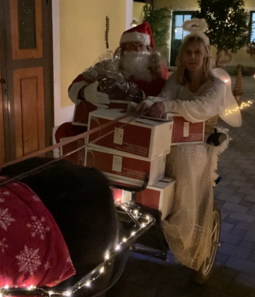 Weihnachtsmann und Christkind auf Kutsche mit Geschenken